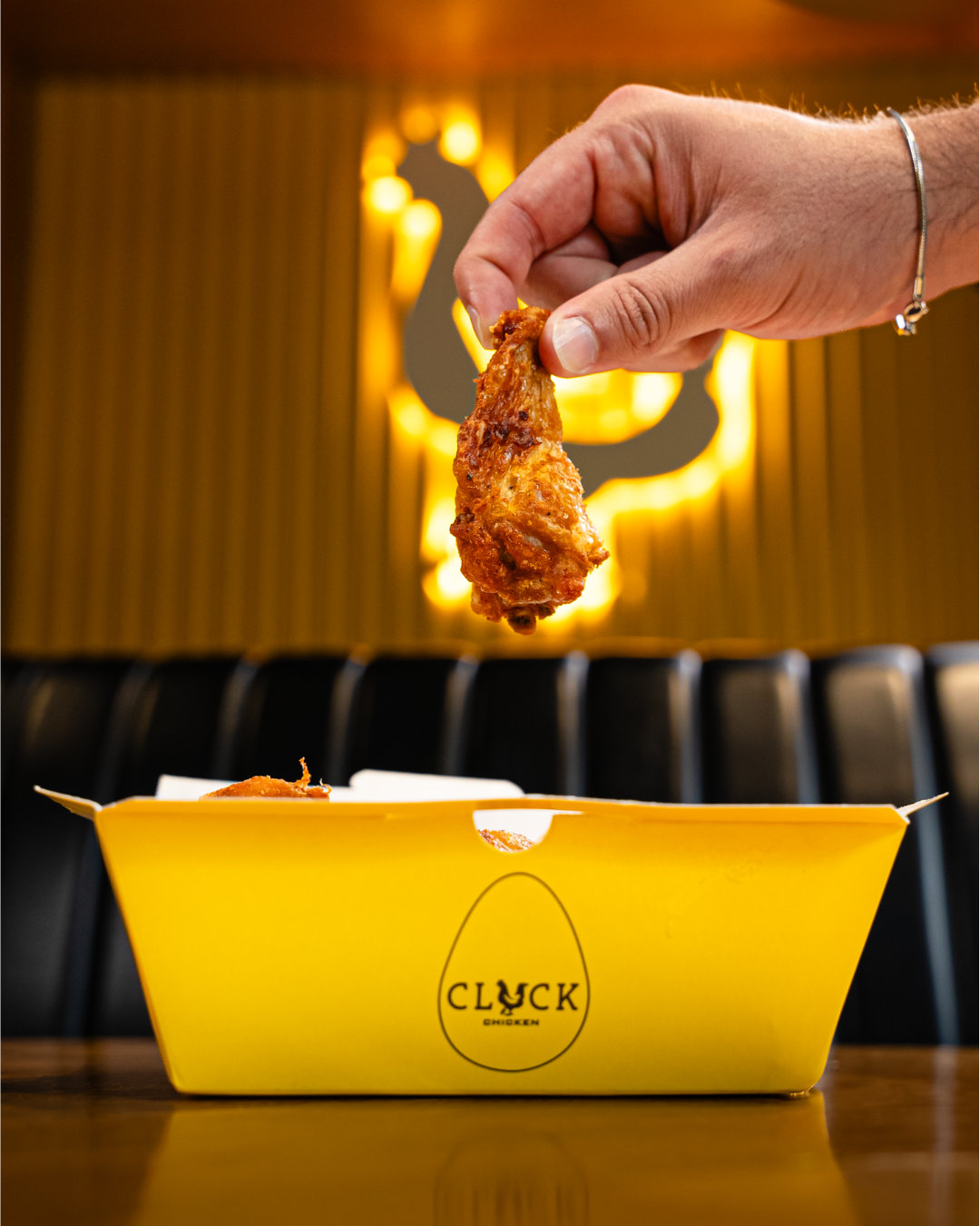 A buttermilk tender lifted out of a yellow Cluck box